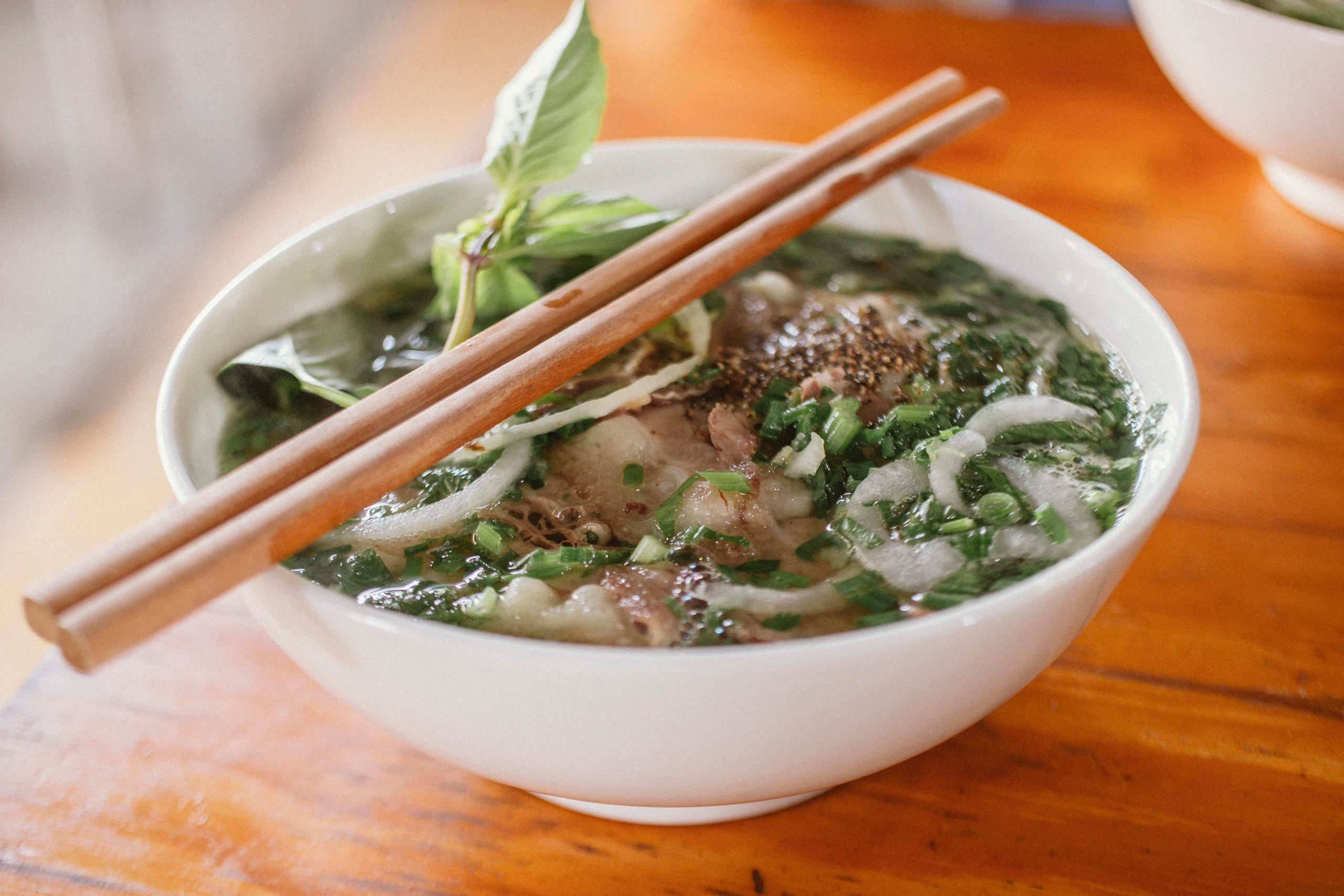 delicious-vietnamese-pho-with-fresh-herbs-and-beef-in-a-ceramic-bowl-served-with-chopsticks-tttAQb6l0SYRHPyV9q1AVg
